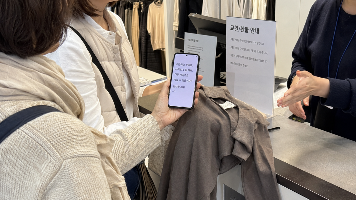 韓国語を見せて服の交換を頼む旅行者