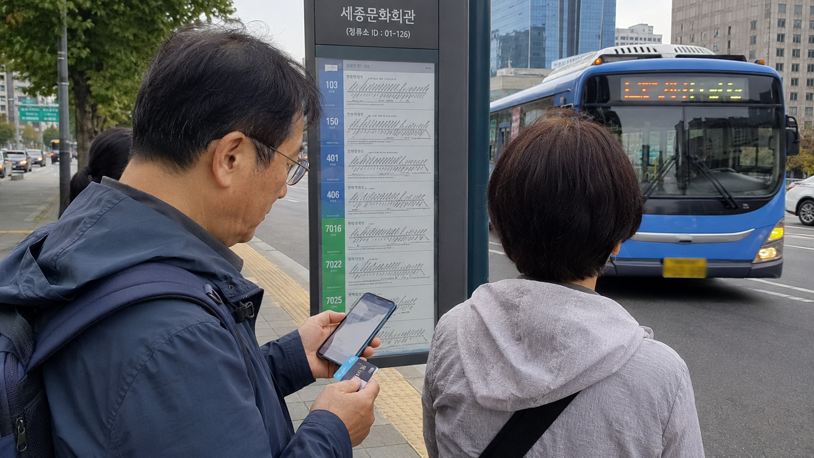 バス停でカードと乗車記録を確認する夫婦